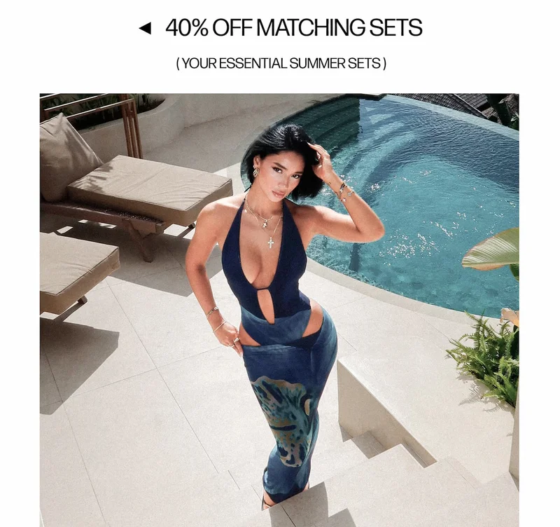 Woman models navy cut-out swimsuit and matching patterned sarong set by pool. Shop 40% off essential summer matching sets!