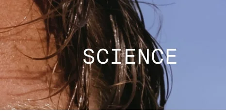 Word 'SCIENCE' in white text over close-up of wet hair against blue sky.