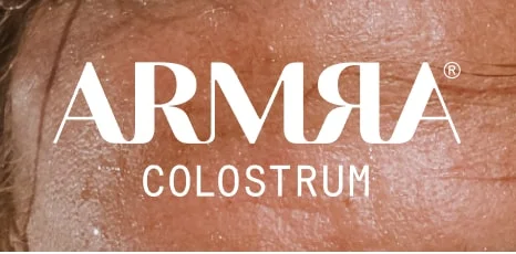 ARMRA Colostrum logo in white text over close-up skin texture.