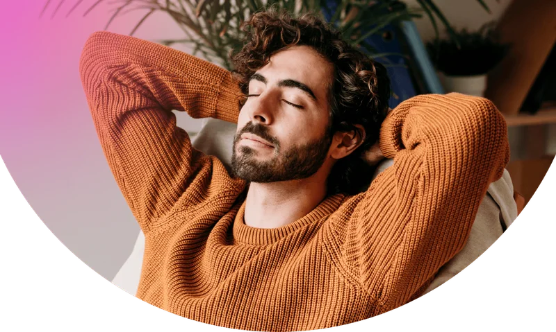 Young man with eyes closed sitting on armchair at home