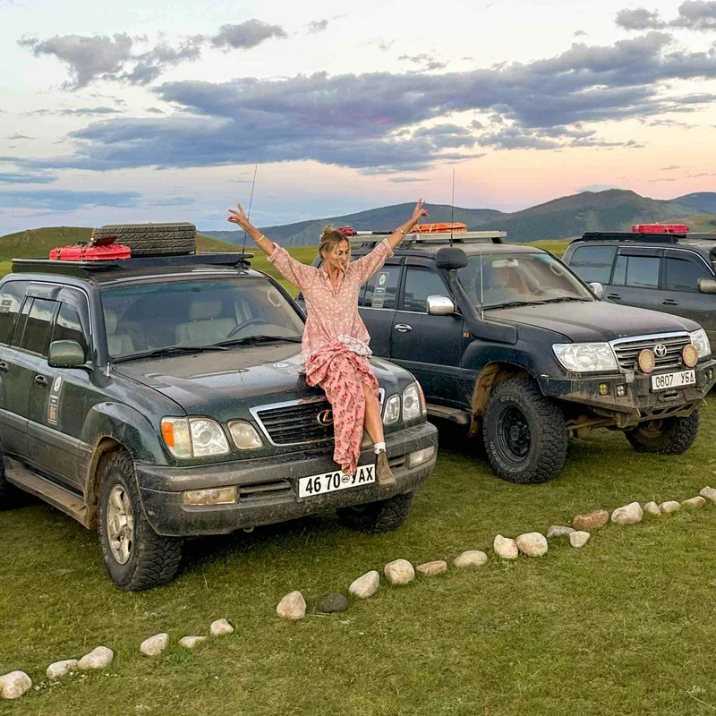 Woman sitting on a car in Mongolia.