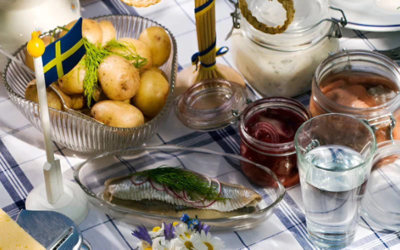 A table spread of boiled potatoes, picked onions, smoked salmon, cheese, and more.
