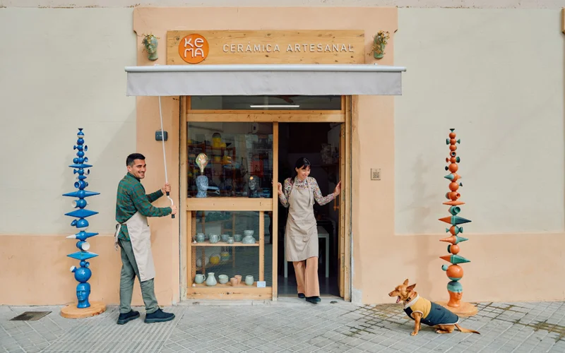 A woman stands smiling in the doorway of a ceramics store.