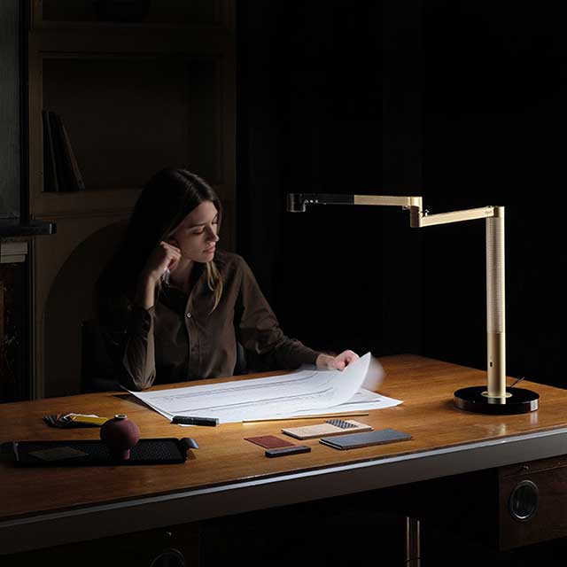 Owner sat at her desk doing work with the Dyson Solarcycle Morph desk light and Dyson Solarcycle Morph floor light.