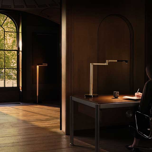 Owner sat at her desk doing work with the Dyson Solarcycle Morph desk light and Dyson Solarcycle Morph floor light.