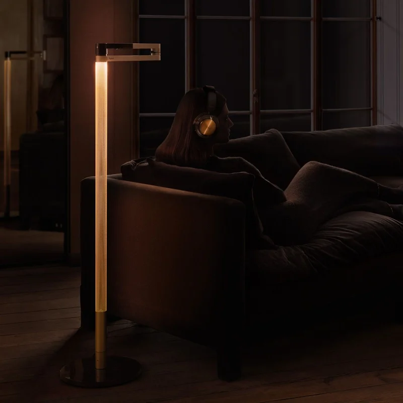 Owner of Dyson OnTrac headphones sat on the sofa with the Dyson Solarcycle Morph floor light.