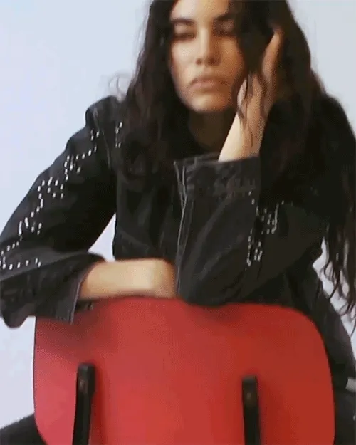 Gif of a person wearing dark wash trucker jacket and jeans while sitting on a chair