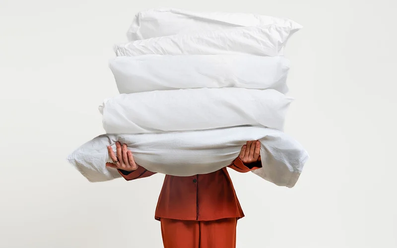 A person holds several pillows.