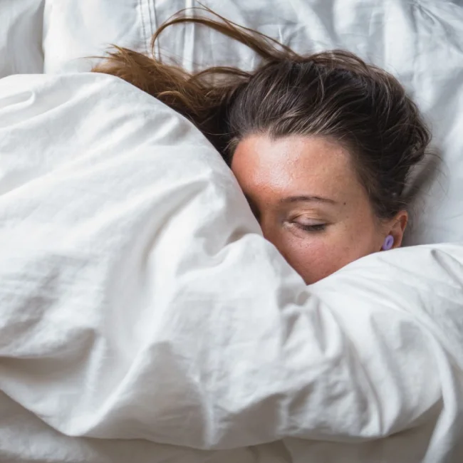 A woman rests peacefully under a fluffy duvet.