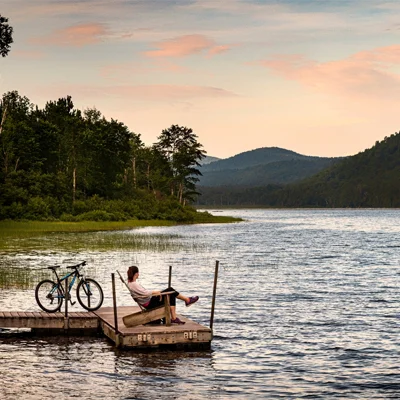 A women sitting on a dock overlooking a lake