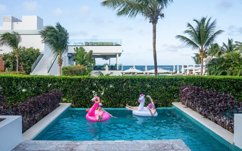 Two individuals play on floaties in a pool at a resort