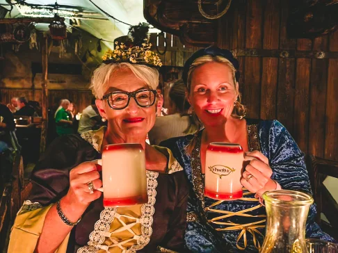 Image Description: Two people toasting with mugs.