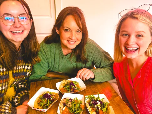 Image Description: Three people smiling with tacos.