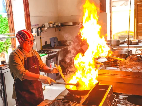 Image Description: A person cooking over a flaming stove.