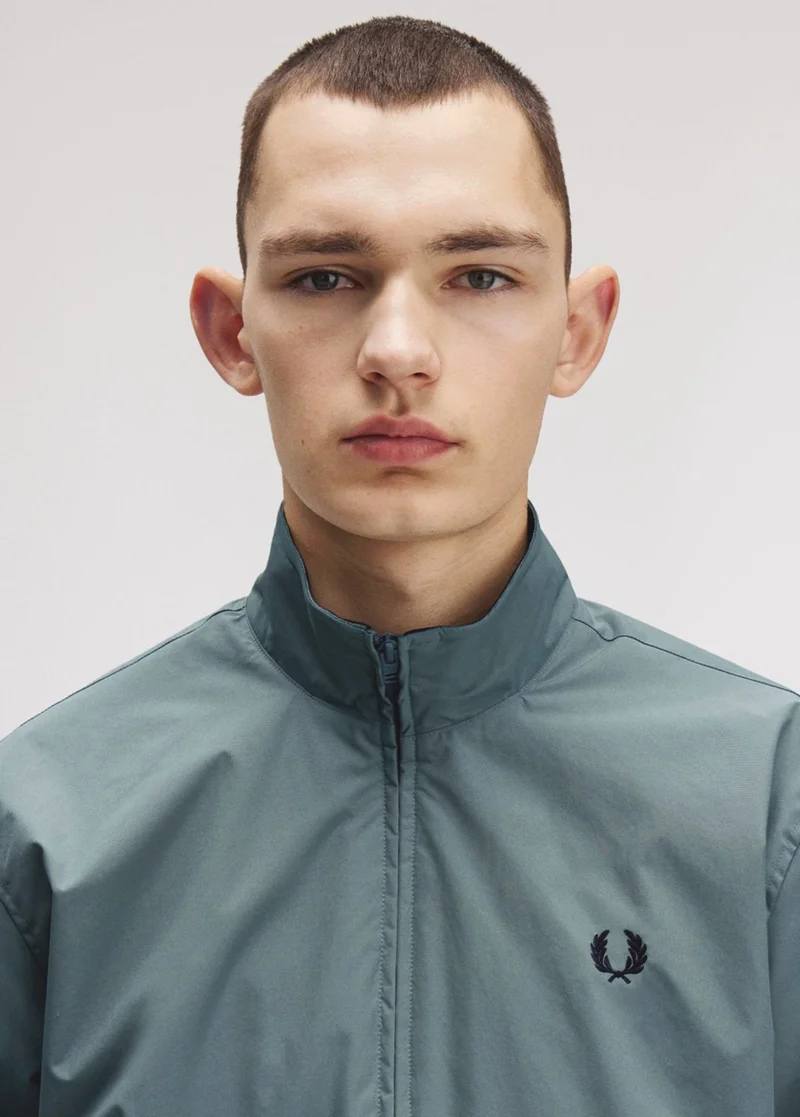 A close up shot of a model wearing a Fred Perry Brentham Jacket in Stockport Blue