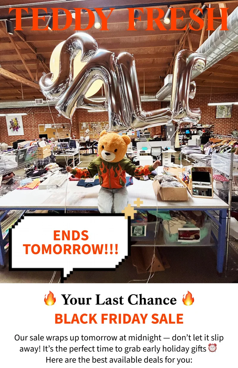 Teddy Fresh bear sat on a work table in the Teddy Fresh Office wearing our Zip Flames Bomber Jacket holding balloons that say SALE.
