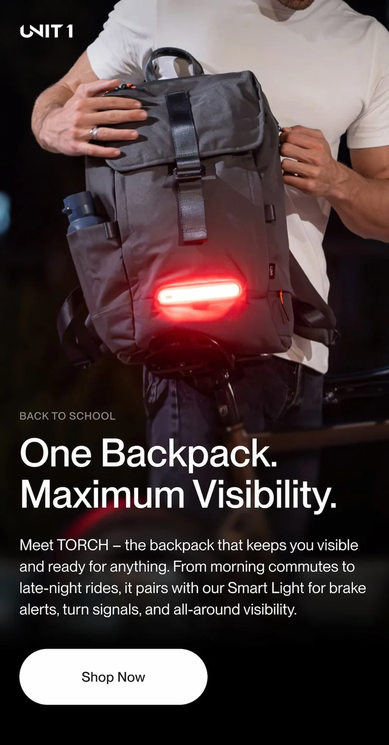 Person wearing UNIT 1 TORCH backpack with Smart Light illuminated, riding at night — Back to School campaign.