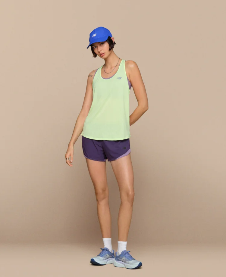 Woman pictured in New Balance shoes and apparel, including the RC Essential Tank and NB Essential Run Bra