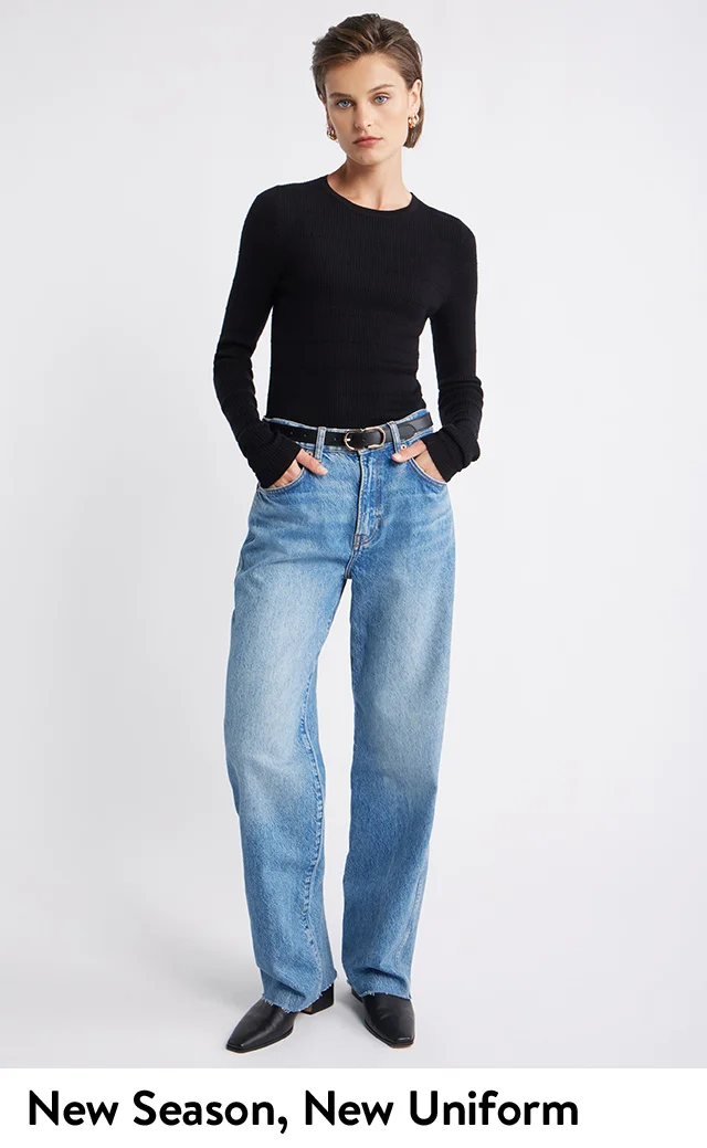A woman wearing a lightweight sweater, jeans, black belt and matching shoes.