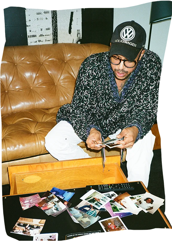 artist sitting on couch in hotel room making a collage with photos