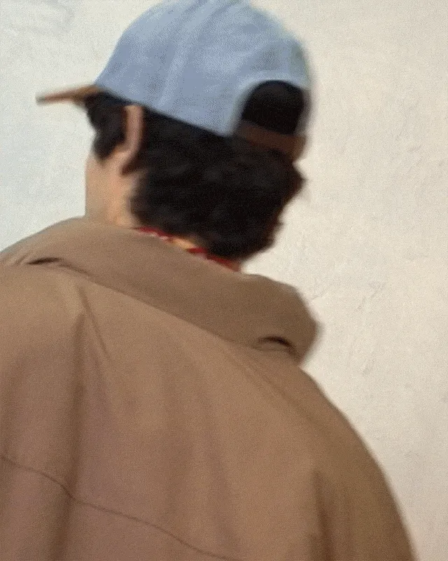Gif of a person wearing a brown jacket, light wash jeans and a hat