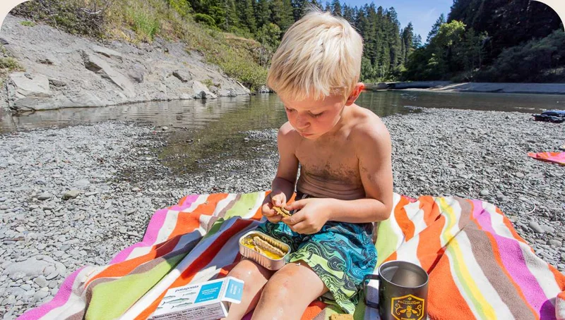 A child eating crackers by a river.