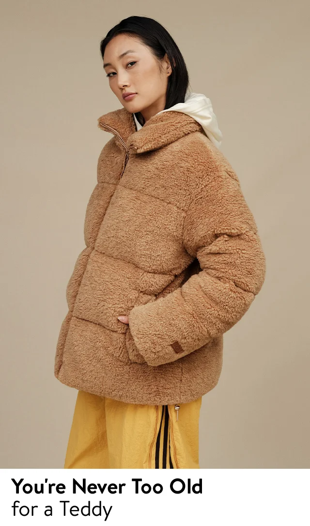 A woman wearing a fluffy brown coat with a white sweatshirt and yellow pants.
