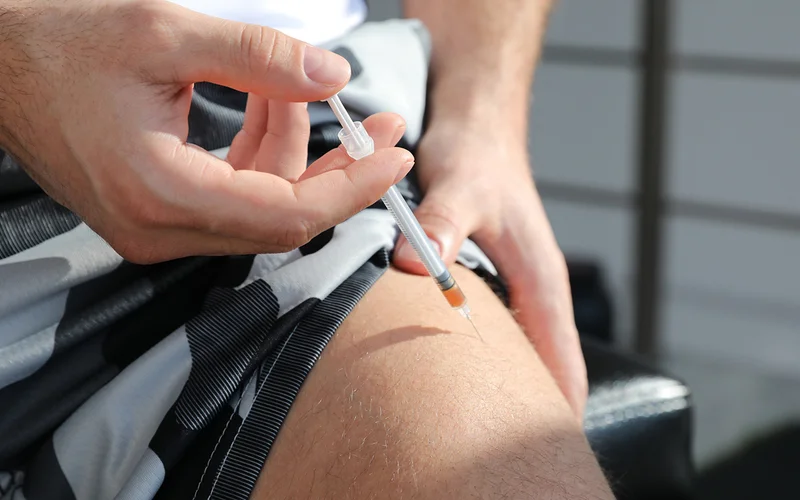A man injects a shot of testosterone into its thigh.