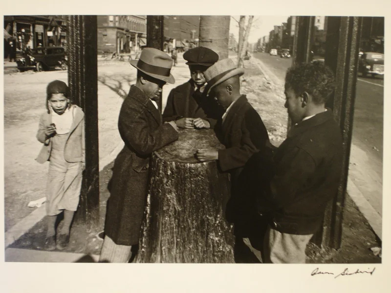 Three boys surround a tree stump while two other children look on