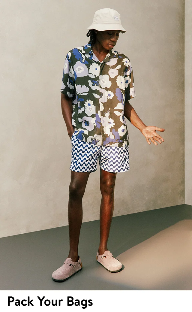 Model wearing a bucket hat, floral-print camp shirt, patterned shorts and Birkenstock mules.