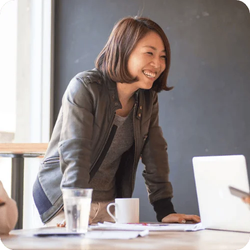 a woman smiling at work because she's not using phrases that women need to stop using a woman smiling at work because she's not using phrases that women need to stop using