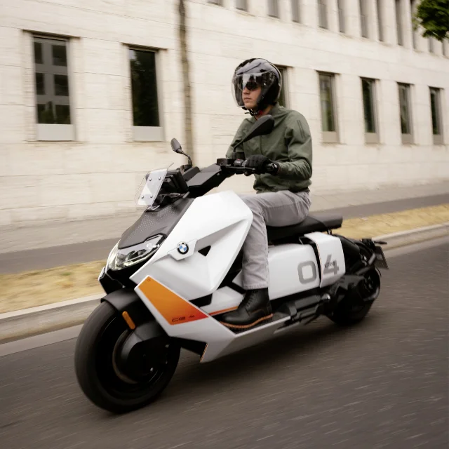 Man riding a white BMW Motorrad CE 04 on a city street.