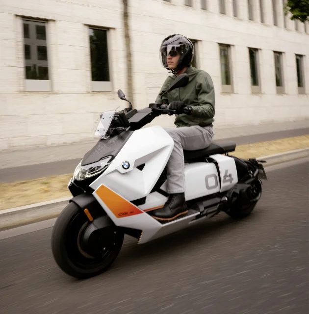 Man riding a white BMW Motorrad CE 04 on a city street.