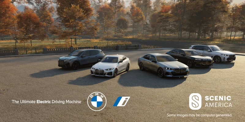BMW vehicles parked in a lot with scenic foliage.