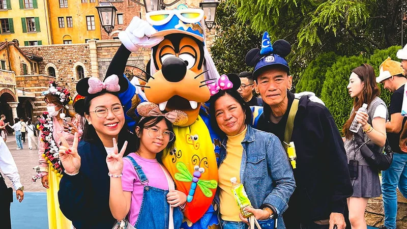 Image description: Family posing for photo with Goofy at Tokyo DisneySea.