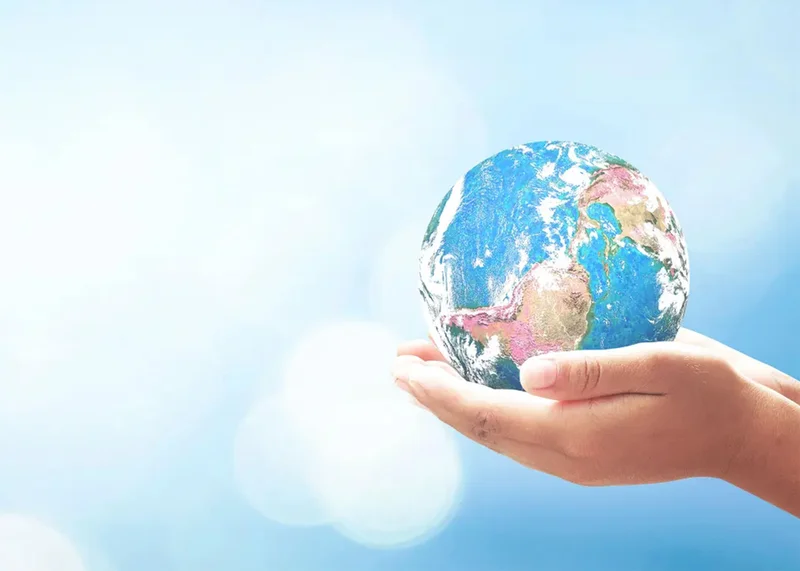 A globe is held in the palms of a person's cupped hands as an illustration of TOTO's commitment to sustainability