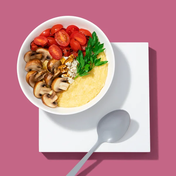 Bowl of polenta topped with mushrooms and tomatoes