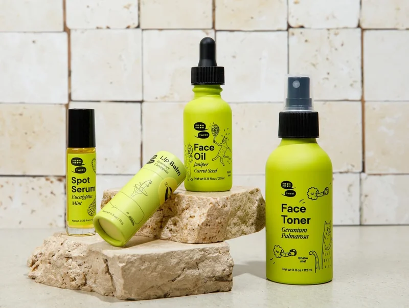Four skincare products in green packaging arranged against slabs of marble.