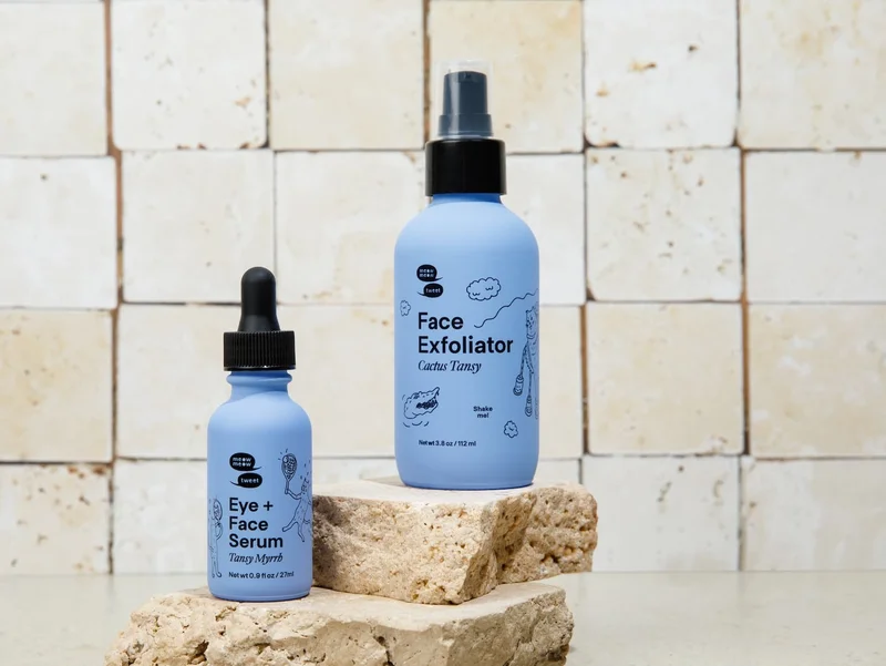 Two skincare products in blue packaging arranged against slabs of marble.