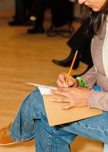 A person writing in a notebook with a pencil