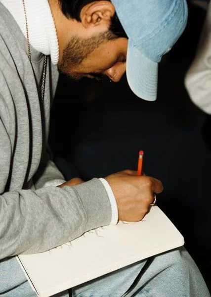 A person writing in a notebook with a red pencil
