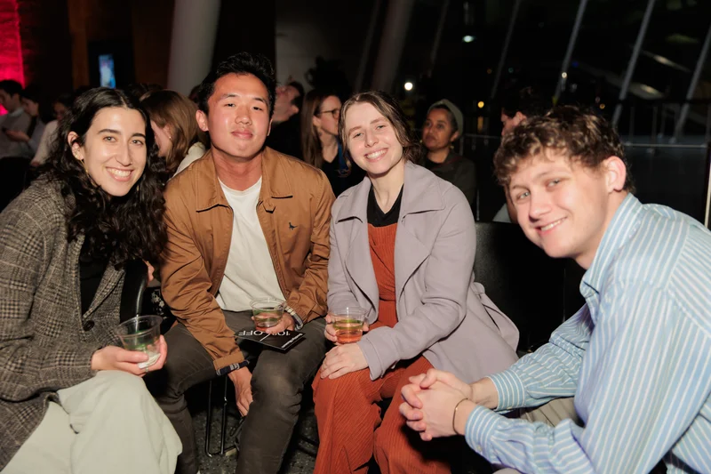 Four seated people smiling and holding drinks