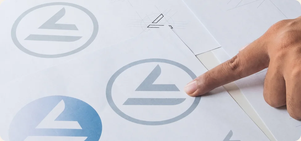 Close up image of a hand pointing at a design in a logo sheet