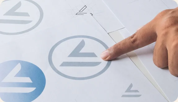Close up image of a hand pointing at a design in a logo sheet