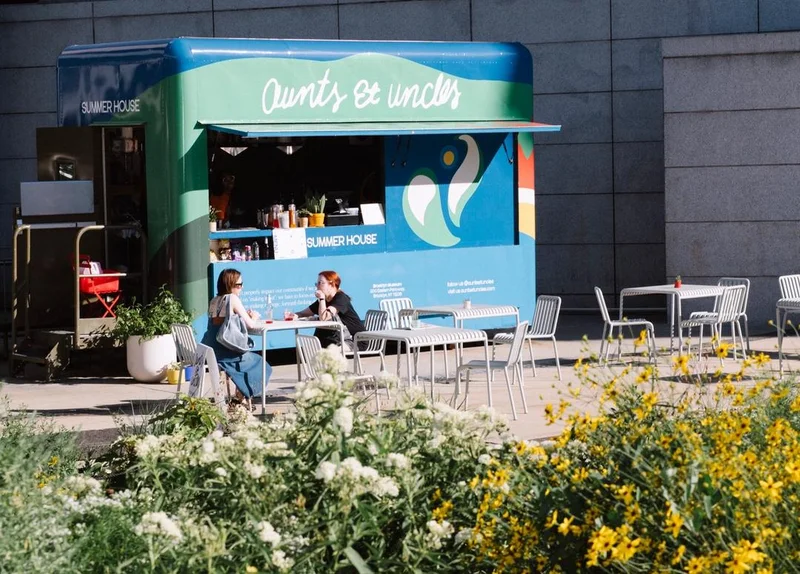 Two people eating at a table next to a food truck
