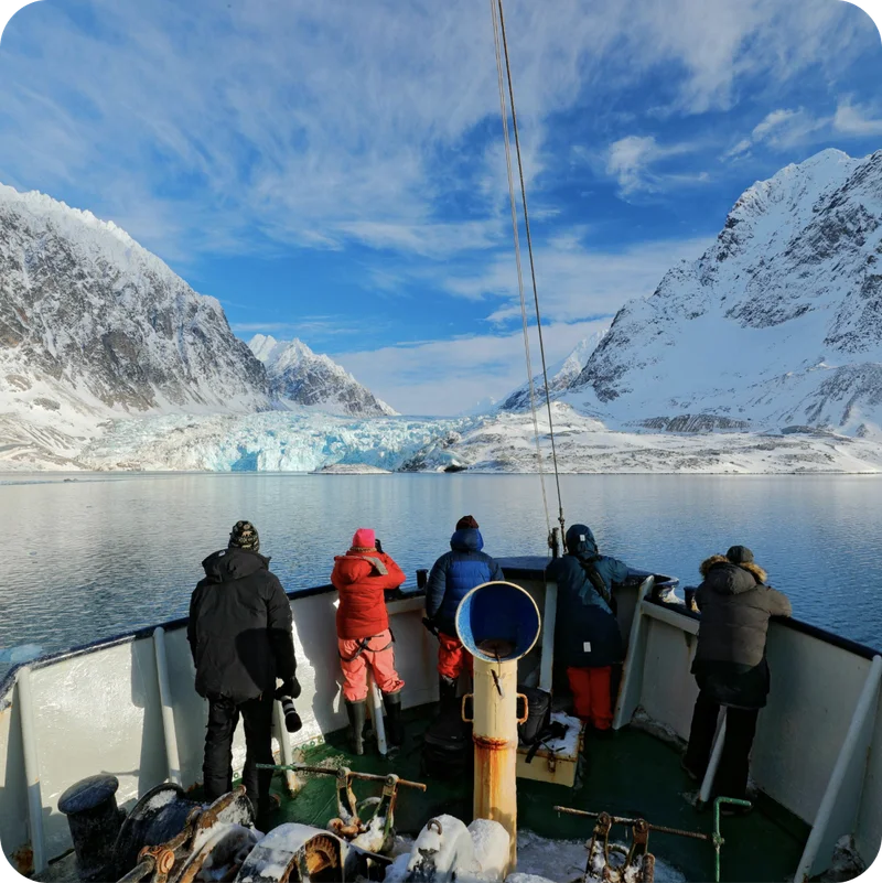 People standing in a boat alongside ice.