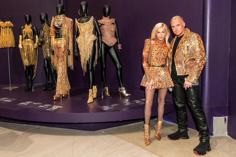 The Blonds wearing gold outfits and standing in front of mannequins wearing gold outfits