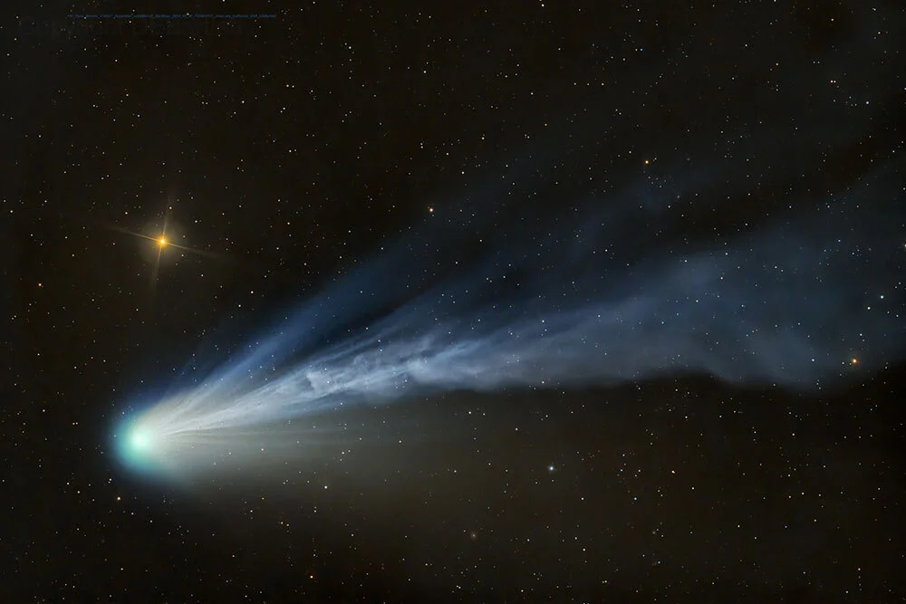 A bright blue comet and its cloud-like tail of particles, seen amongst the stars