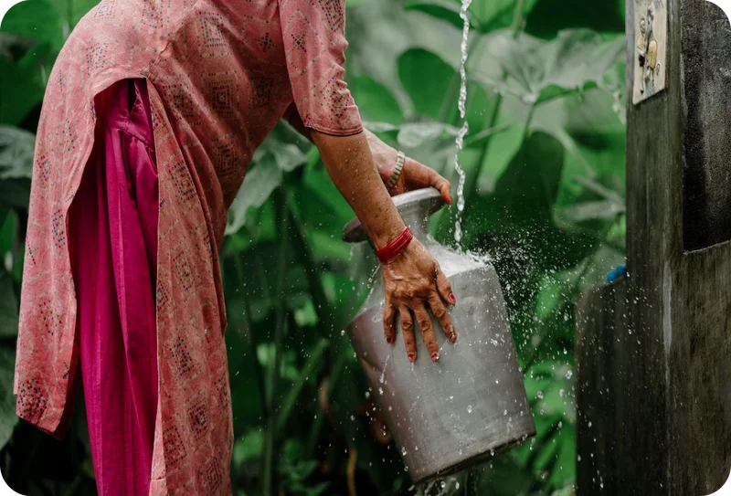 A woman fills up a metal container with water from a water point.