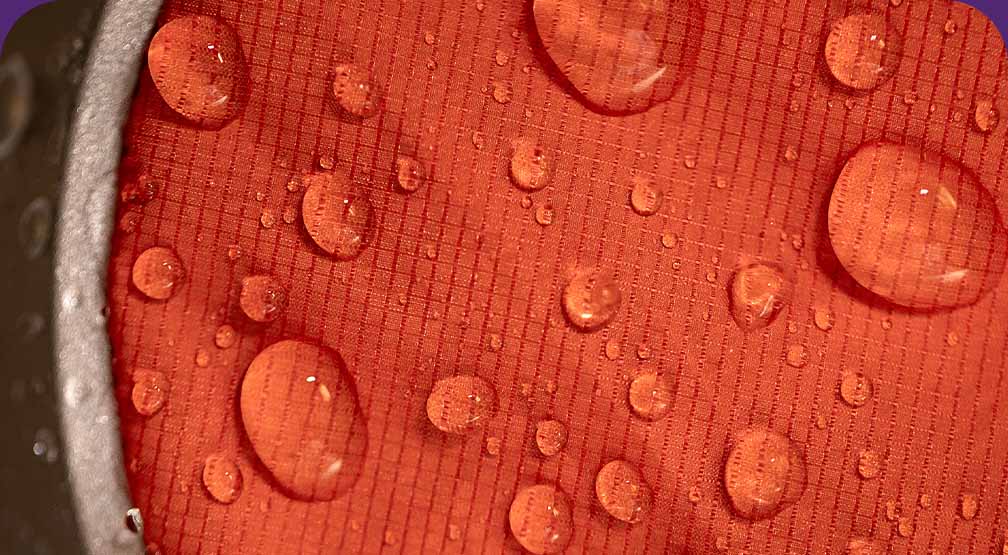 Water beading up on a piece of orange shell fabric being tested in a lab.